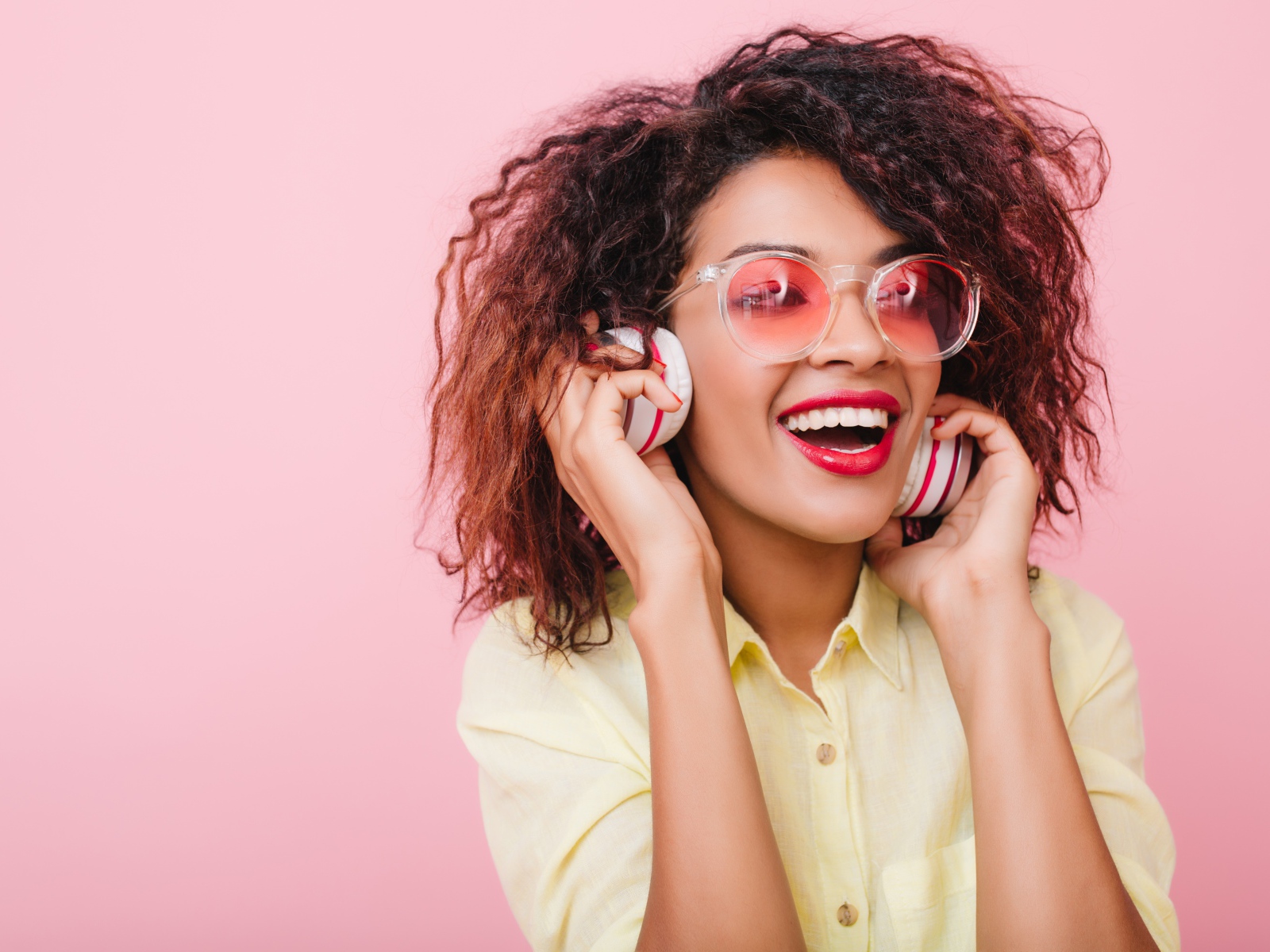 Яркая улыбающаяся девушка слушает музыку в наушниках 