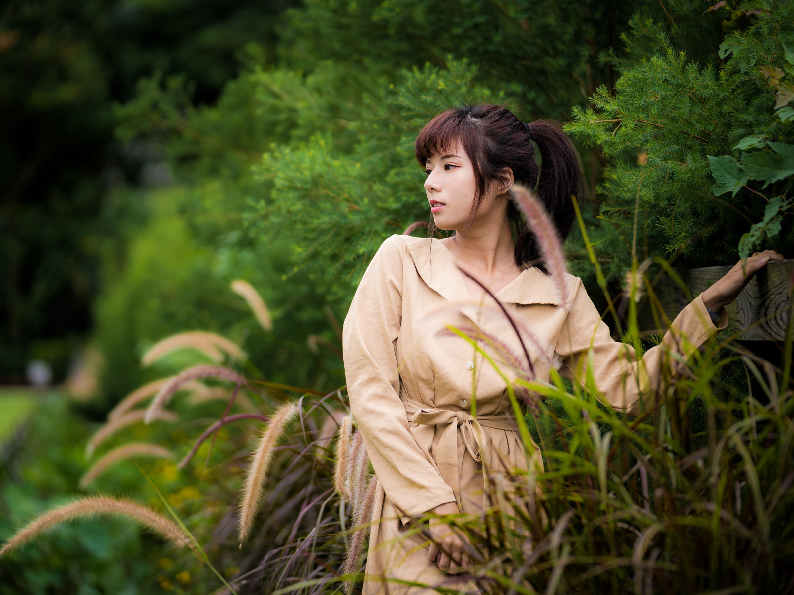 Милая азиатка в пальто в парке 