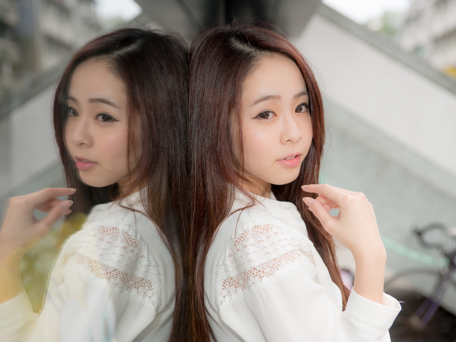 Милая азиатка в белой рубашке отражается в зеркальной поверхности 