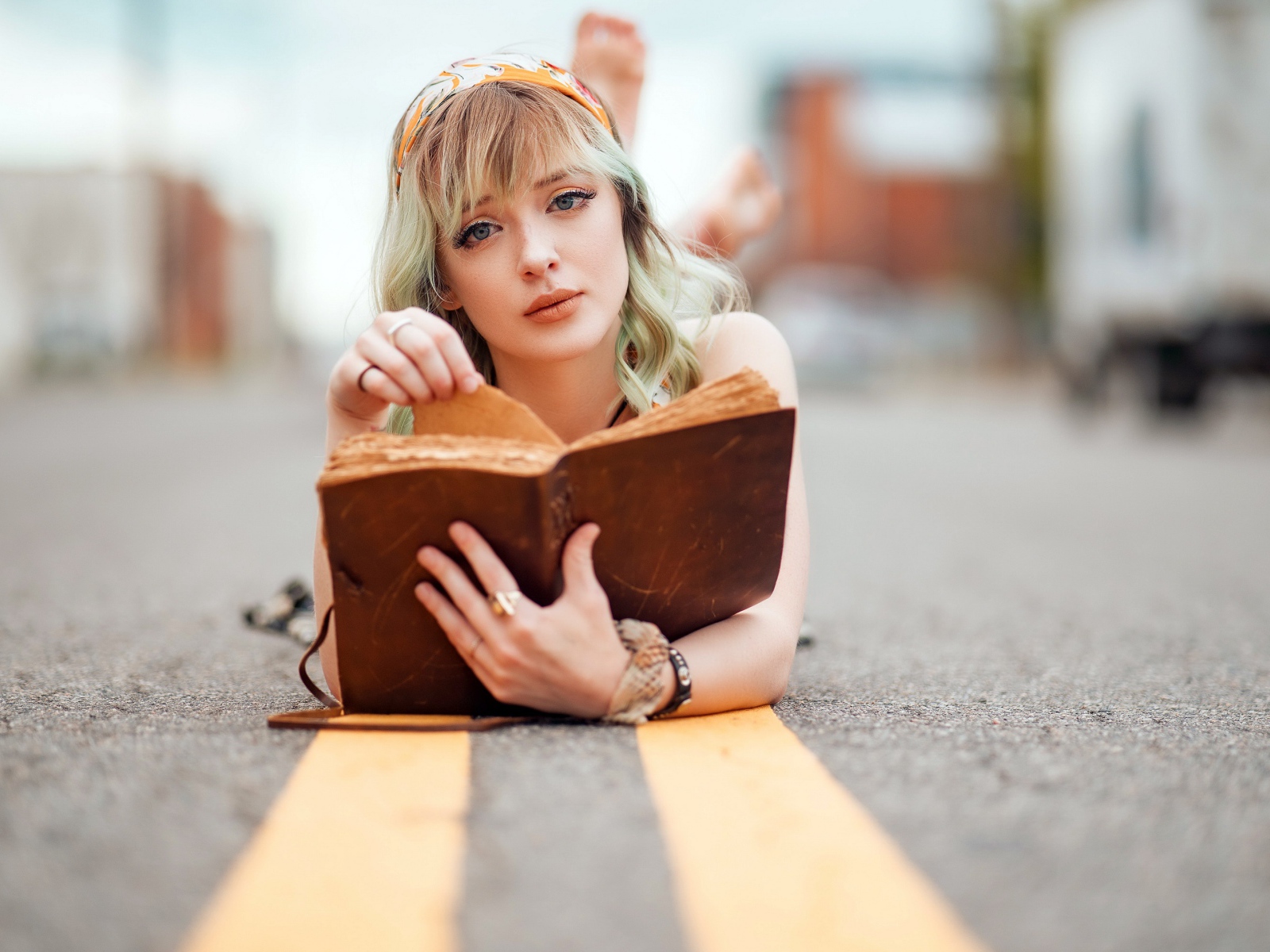 Милая блондинка лежит на асфальте с книгой 