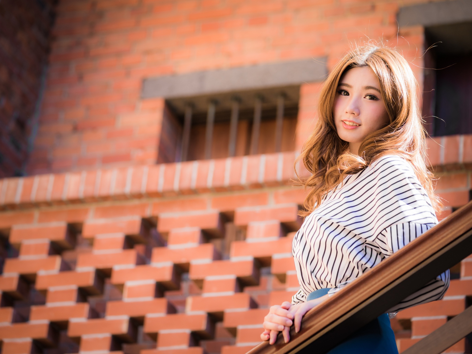 Милая девушка в полосатой рубашке стоит на ступеньках 