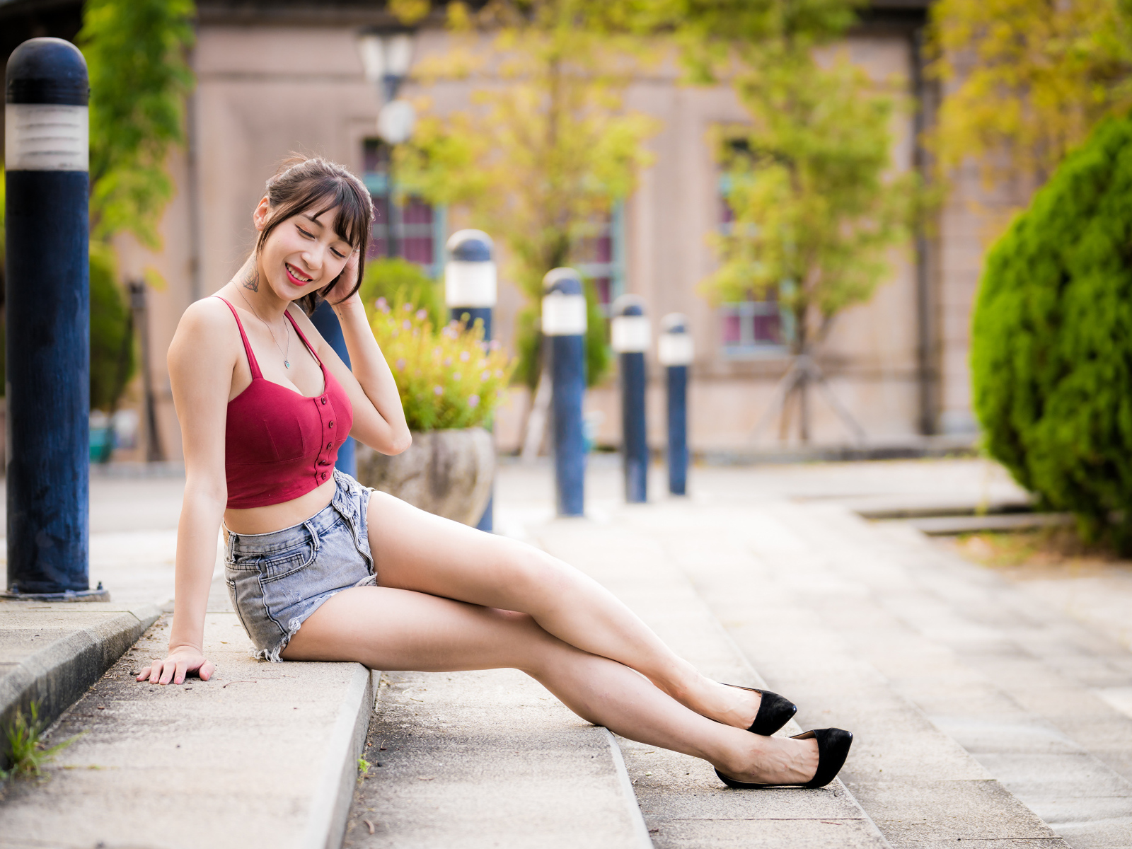 Милая улыбающаяся девушка азиатка сидит на ступенях