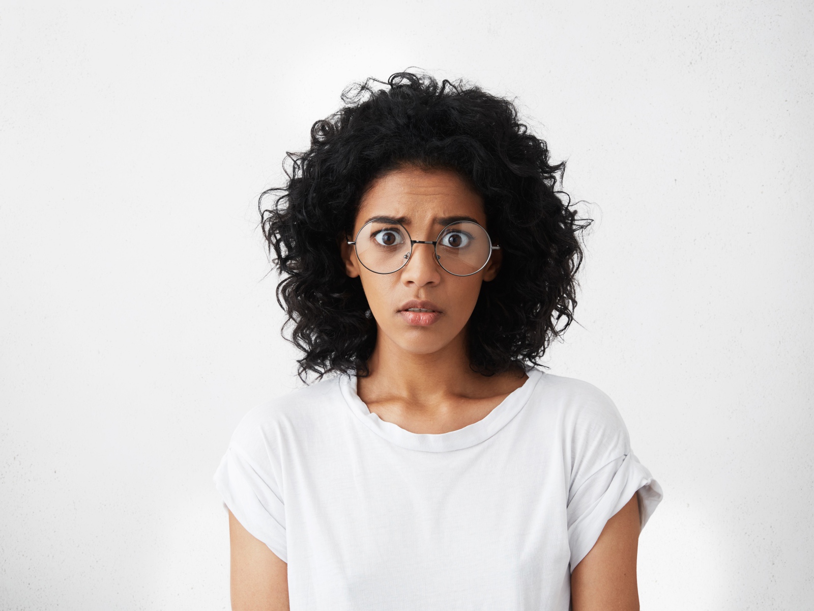 Темноволосая девушка в белой футболке на сером фоне