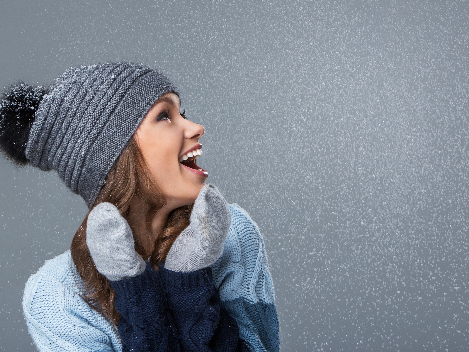Девушка в теплой шапке на сером фоне