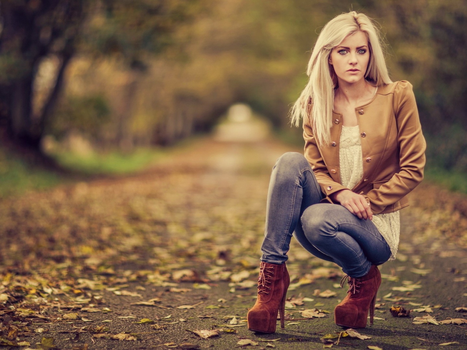 Девушка на высоких каблуках сидит на корточках в парке