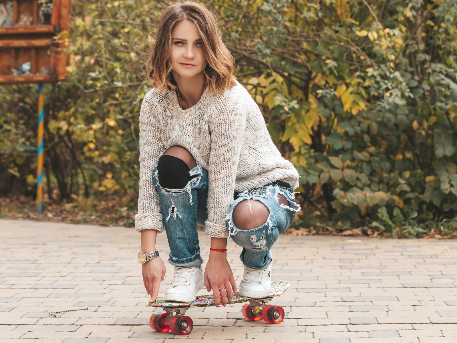 Девушка в рваных джинсах на скейте