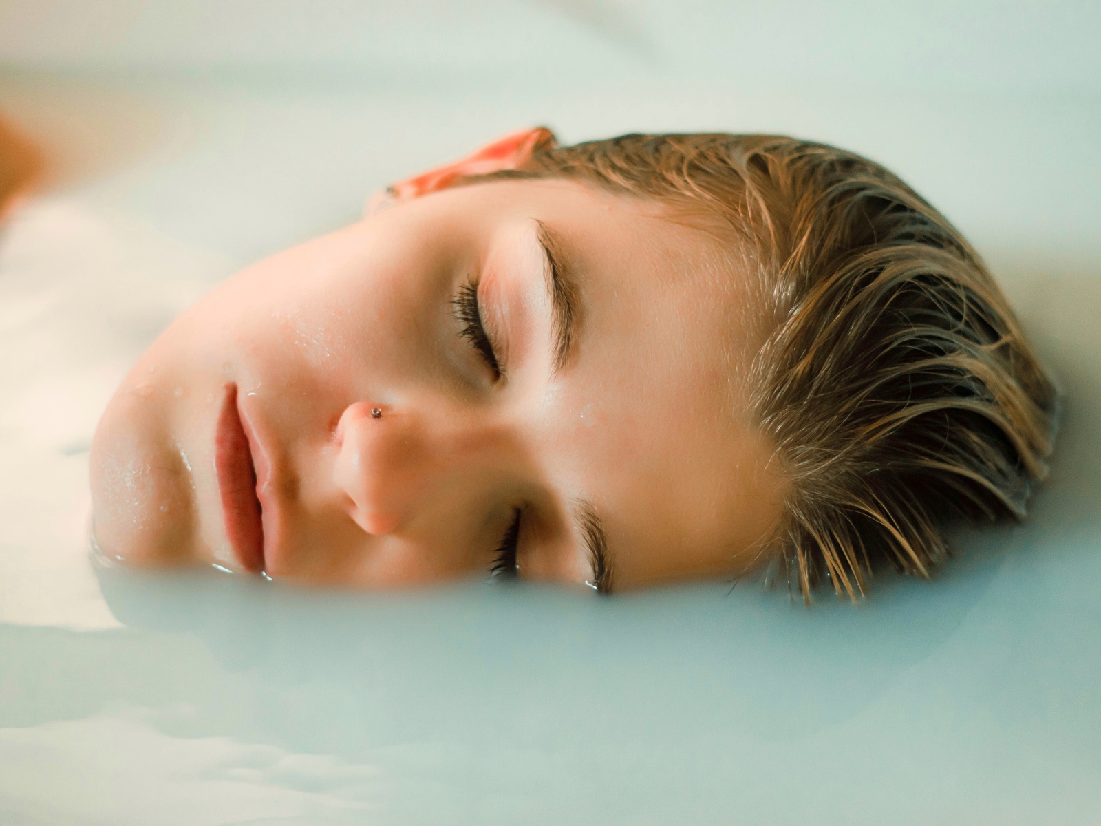 Девушка лежит с закрытыми глазами в ванной