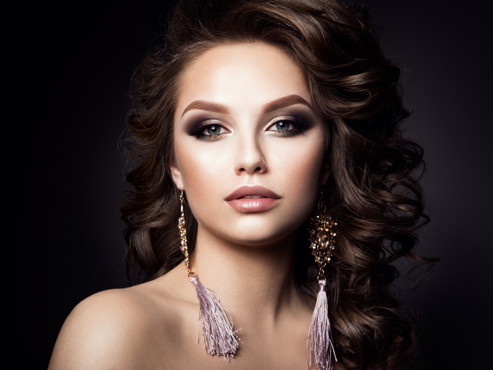 Девушка с прической с красивыми сережками на сером фоне 