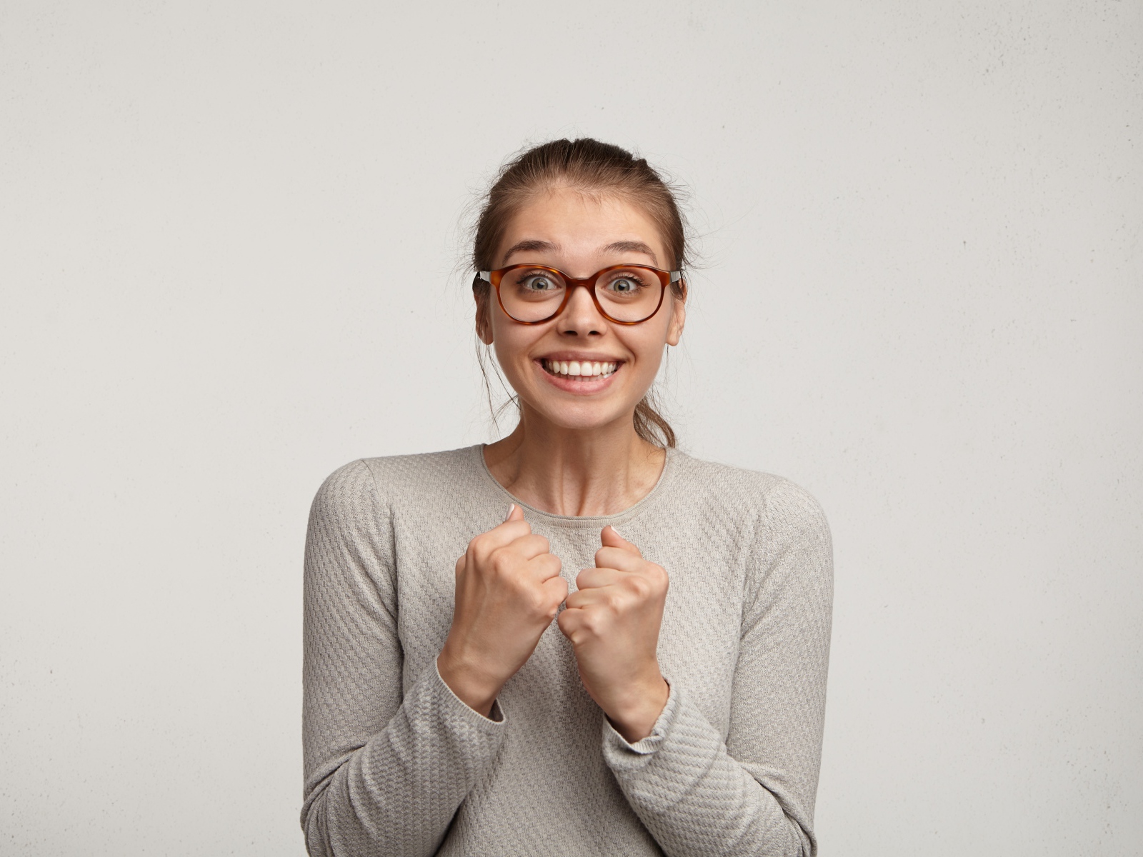 Радостная девушка в очках для зрения на сером фоне 