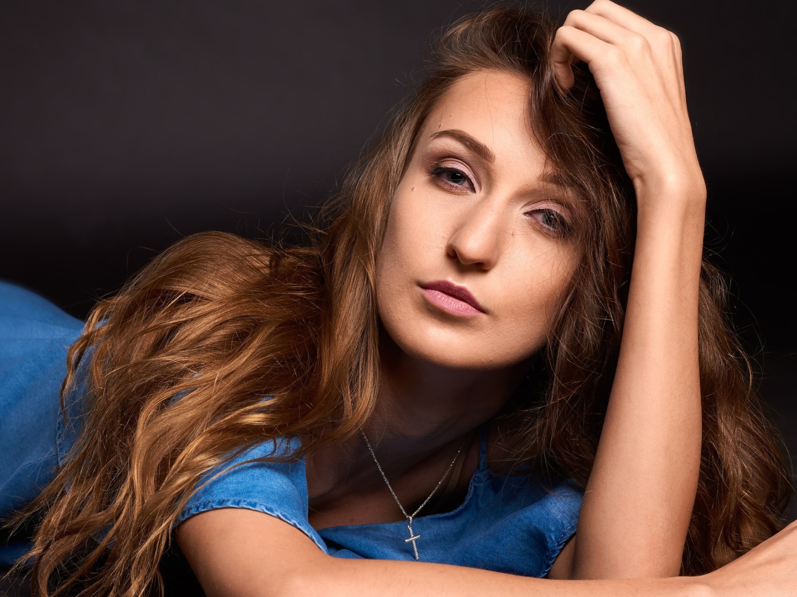 Длинноволосая шатенка лежит на полу в голубом платье 