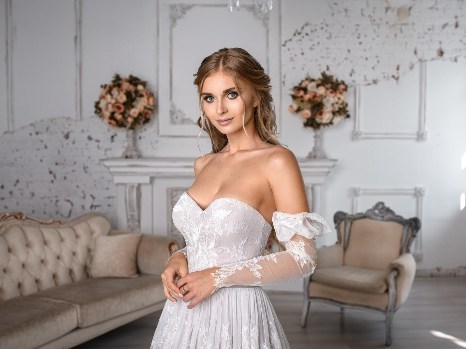 Милая девушка в свадебном платье в комнате с диваном