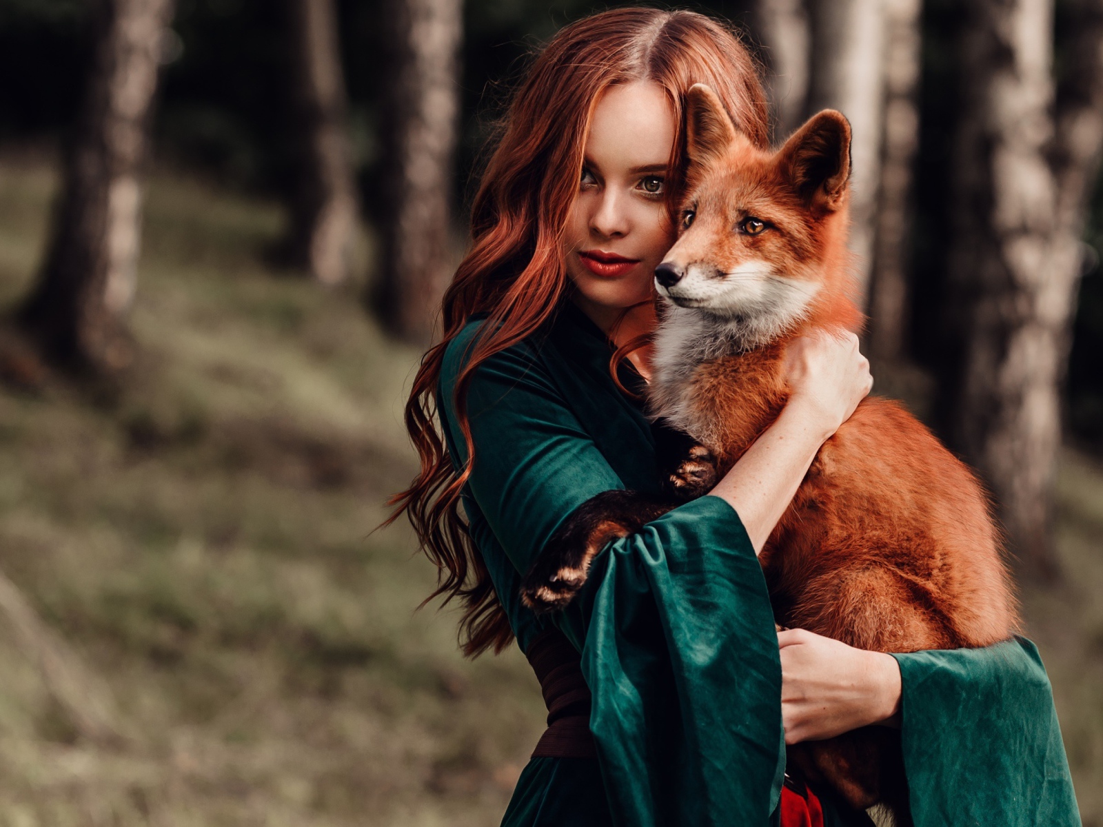 Рыжеволосая девушка в зеленом платье с лисой в руках 