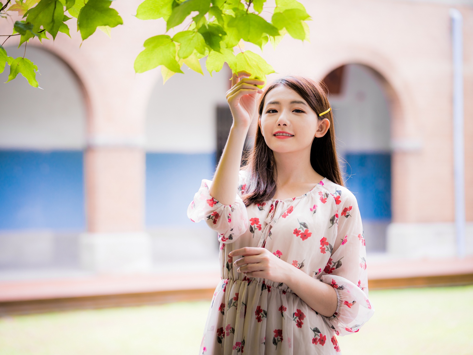 Улыбающаяся девушка в платье у дерева 