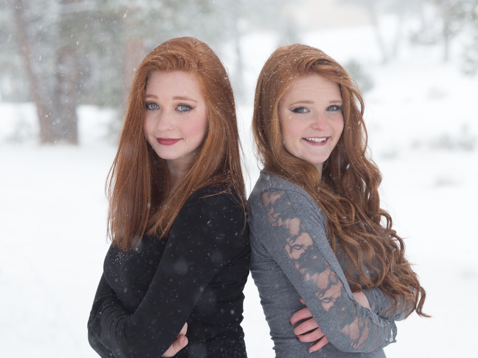 Две улыбающиеся рыжеволосые сестры на улице зимой 