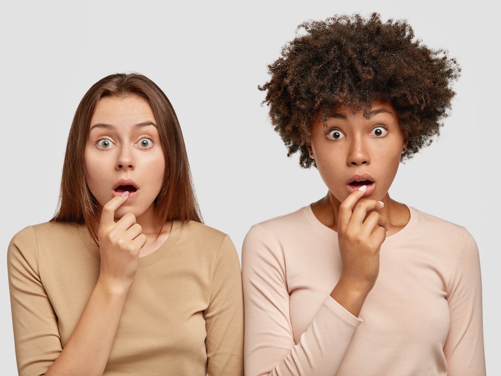 Две удивленные девушки на сером фоне 