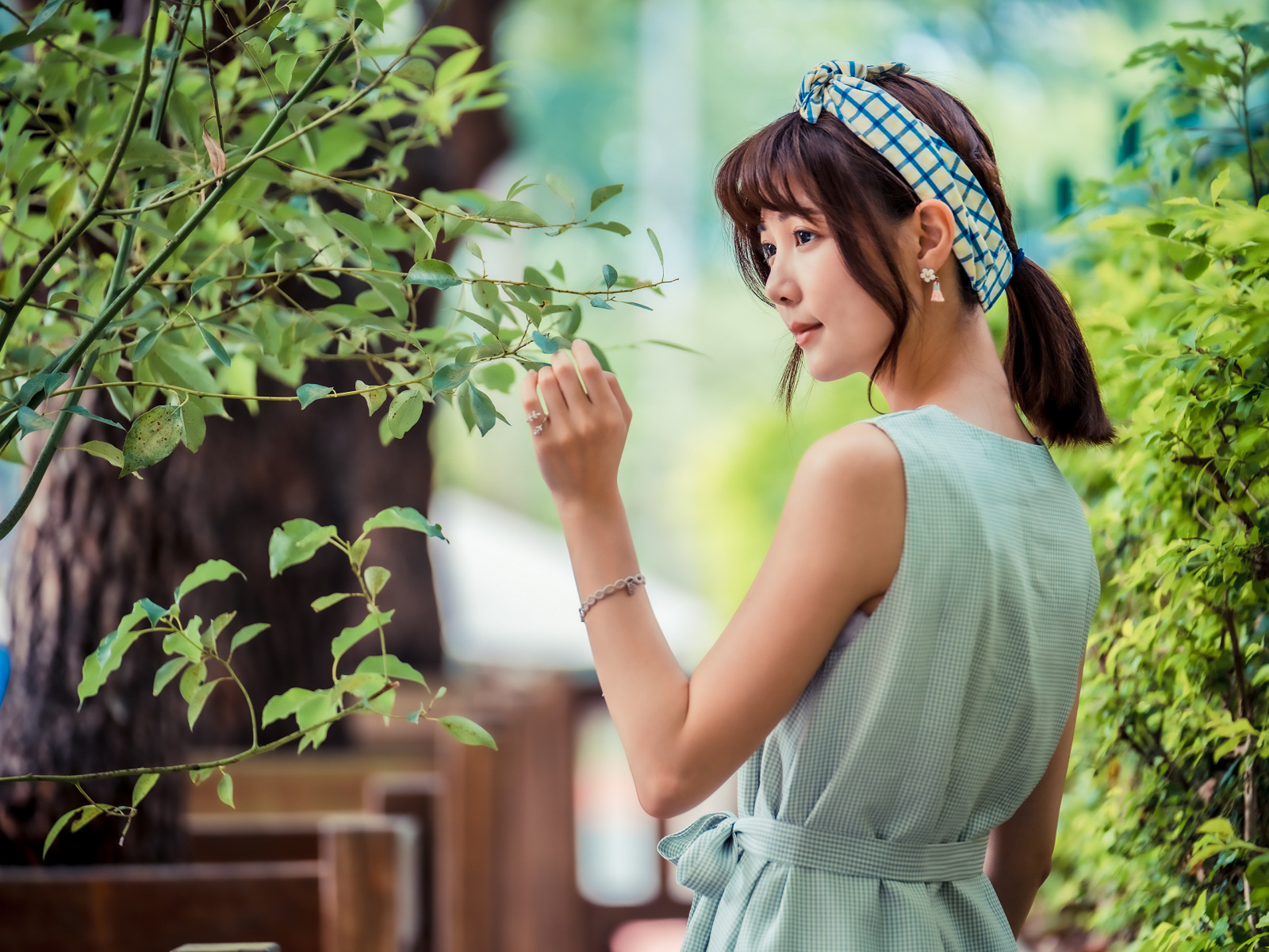 Молодая девушка азиатка с повязкой на голове у дерева 