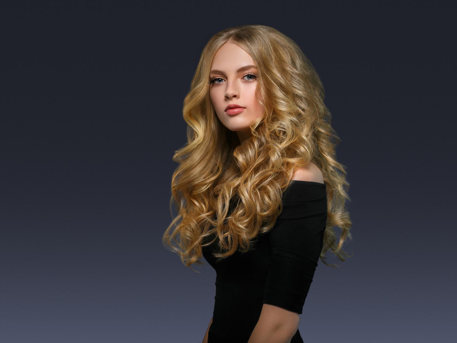 Молодая блондинка с красивыми длинными волосами в черном платье