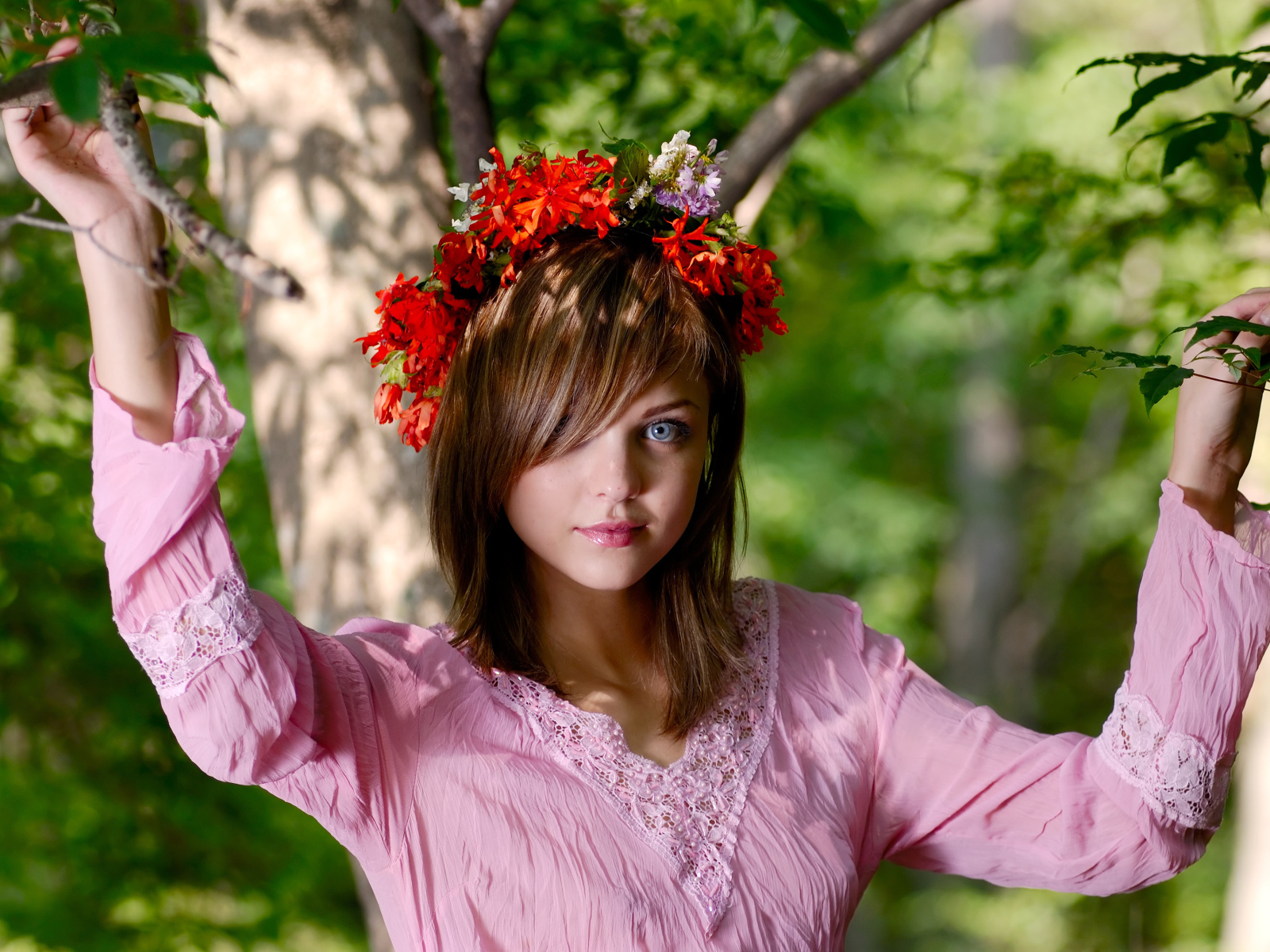 Молодая милая голубоглазая девушка с венком на голове у дерева