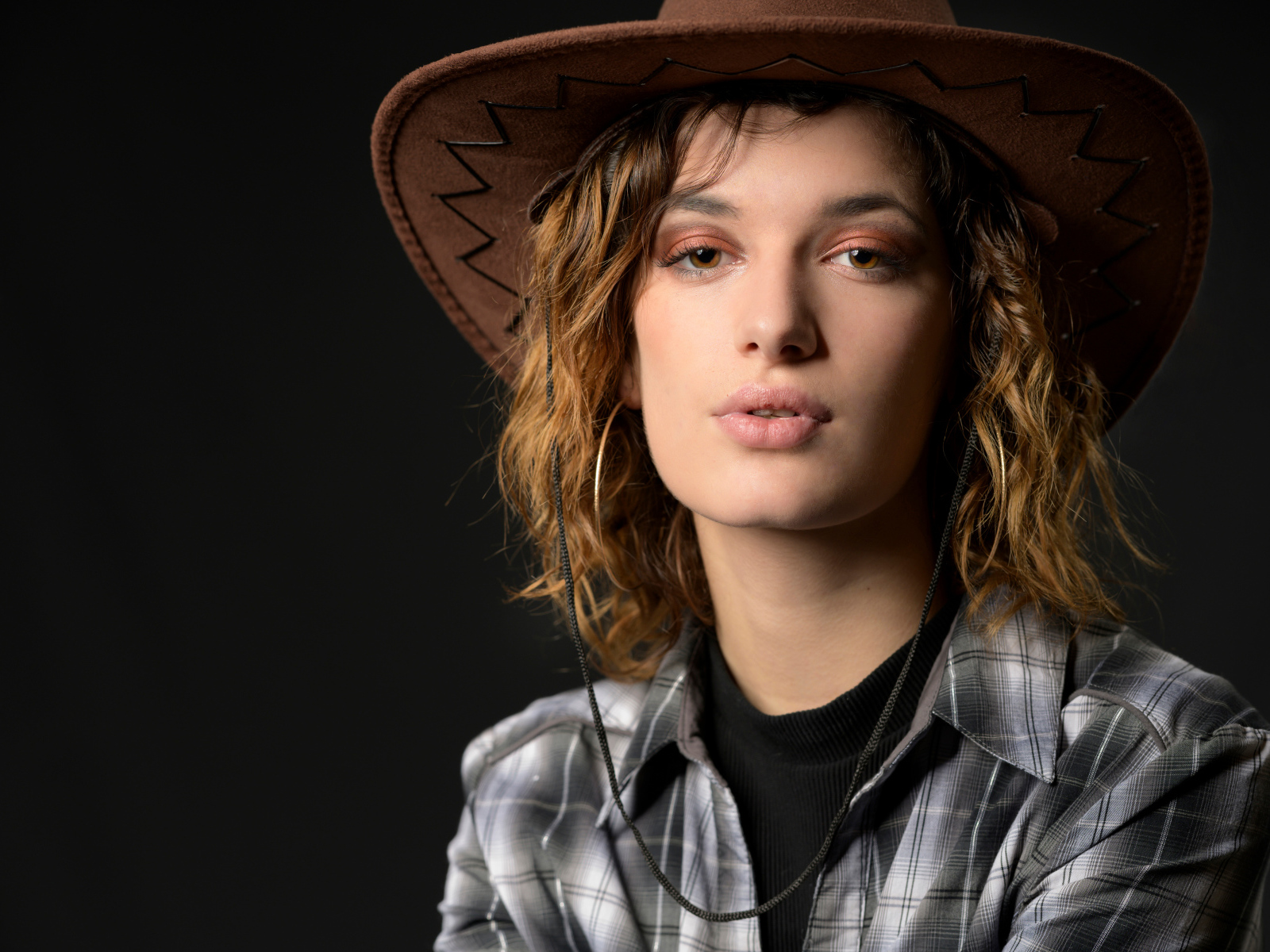 Young girl in a cowboy hat on a gray background