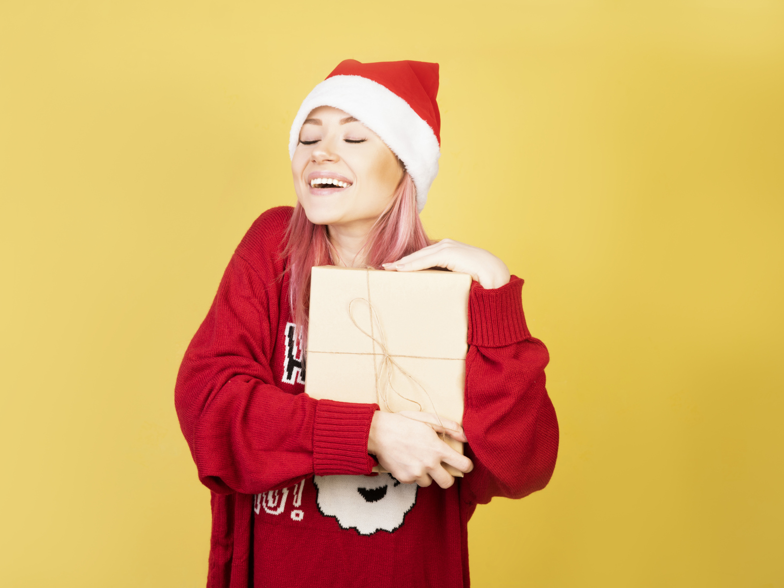 Улыбающаяся девушка в красном свитере с подарком на желтом фоне