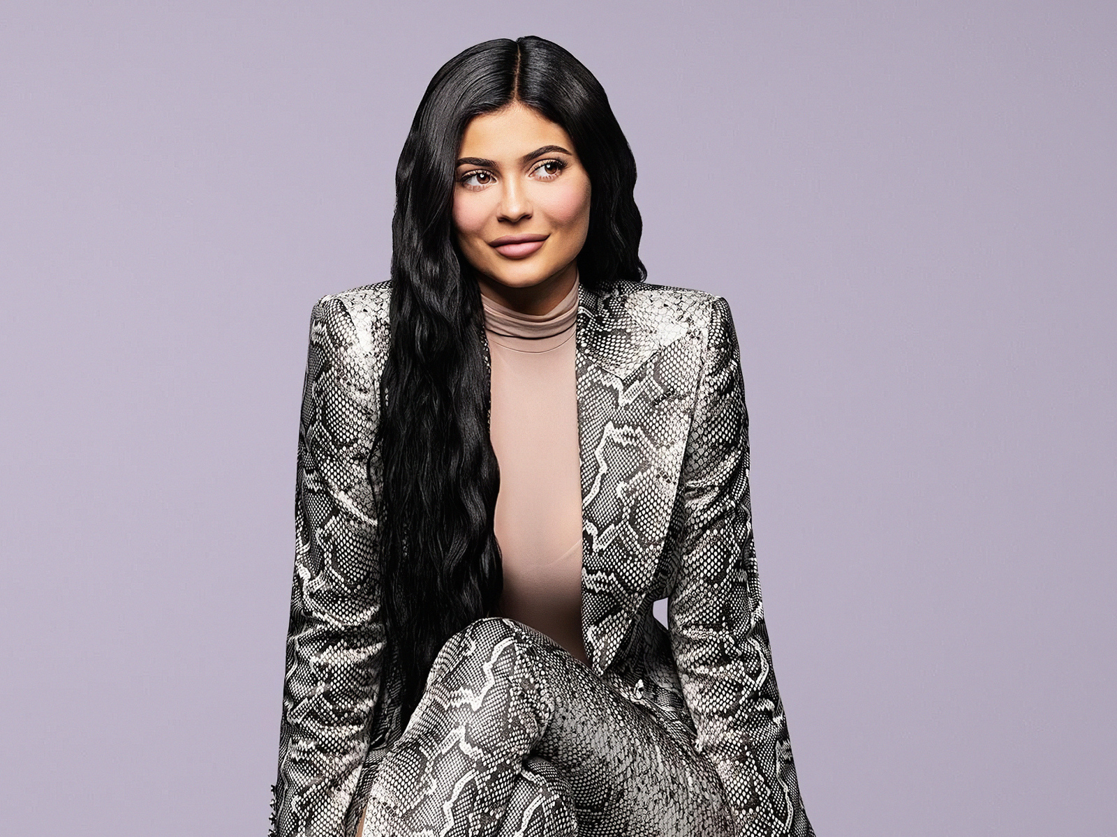 Длинноволосая модель Кайли Дженнер в костюме на сером фоне