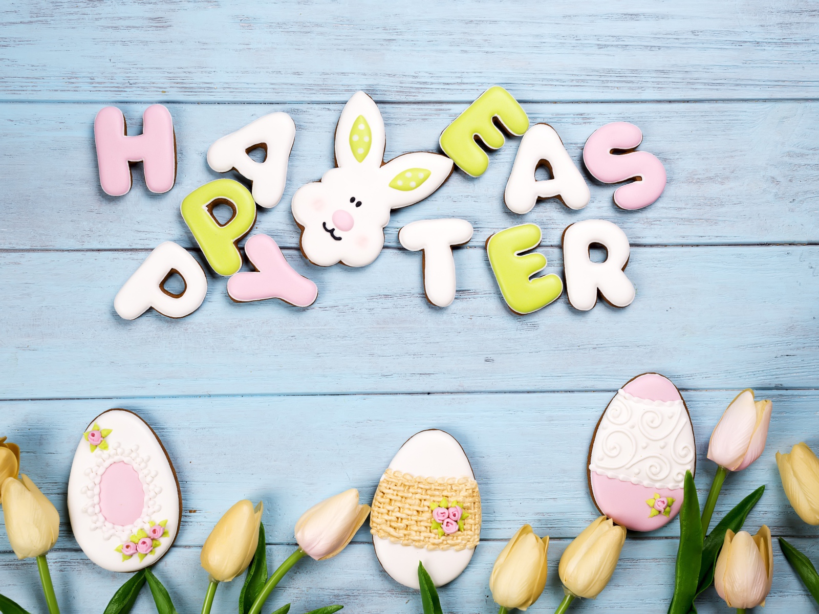 Красивое пасхальное печенье на столе с тюльпанами 