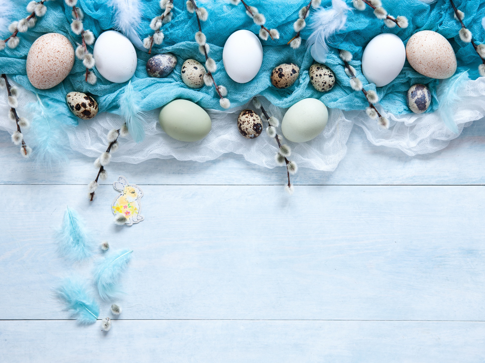 Яйца на ткани с ветками вербы на столе