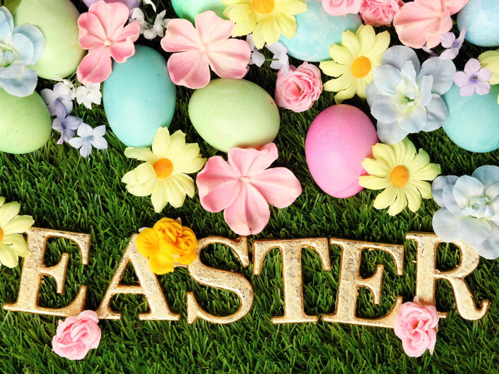 Надпись на траве с разноцветными яйцами и цветами на Пасху