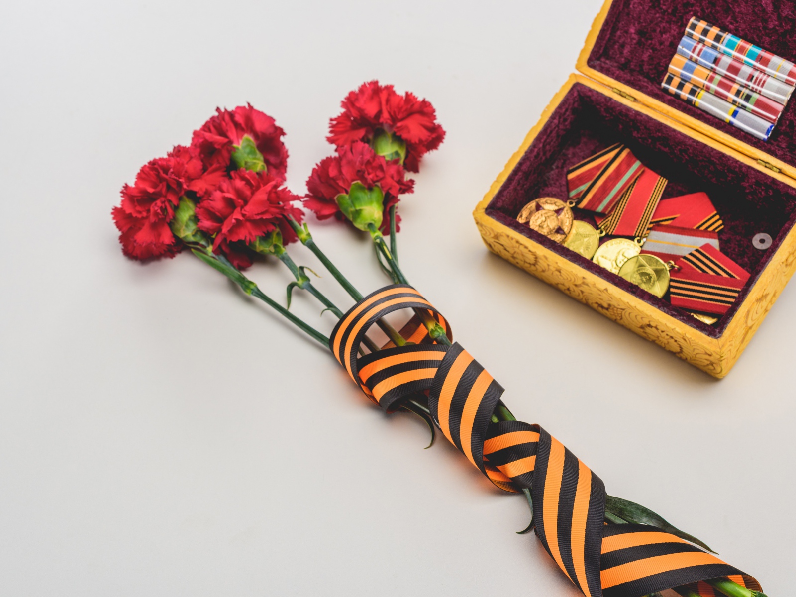 Букет гвоздик с георгиевской лентой и наградами на День Победы 9 мая