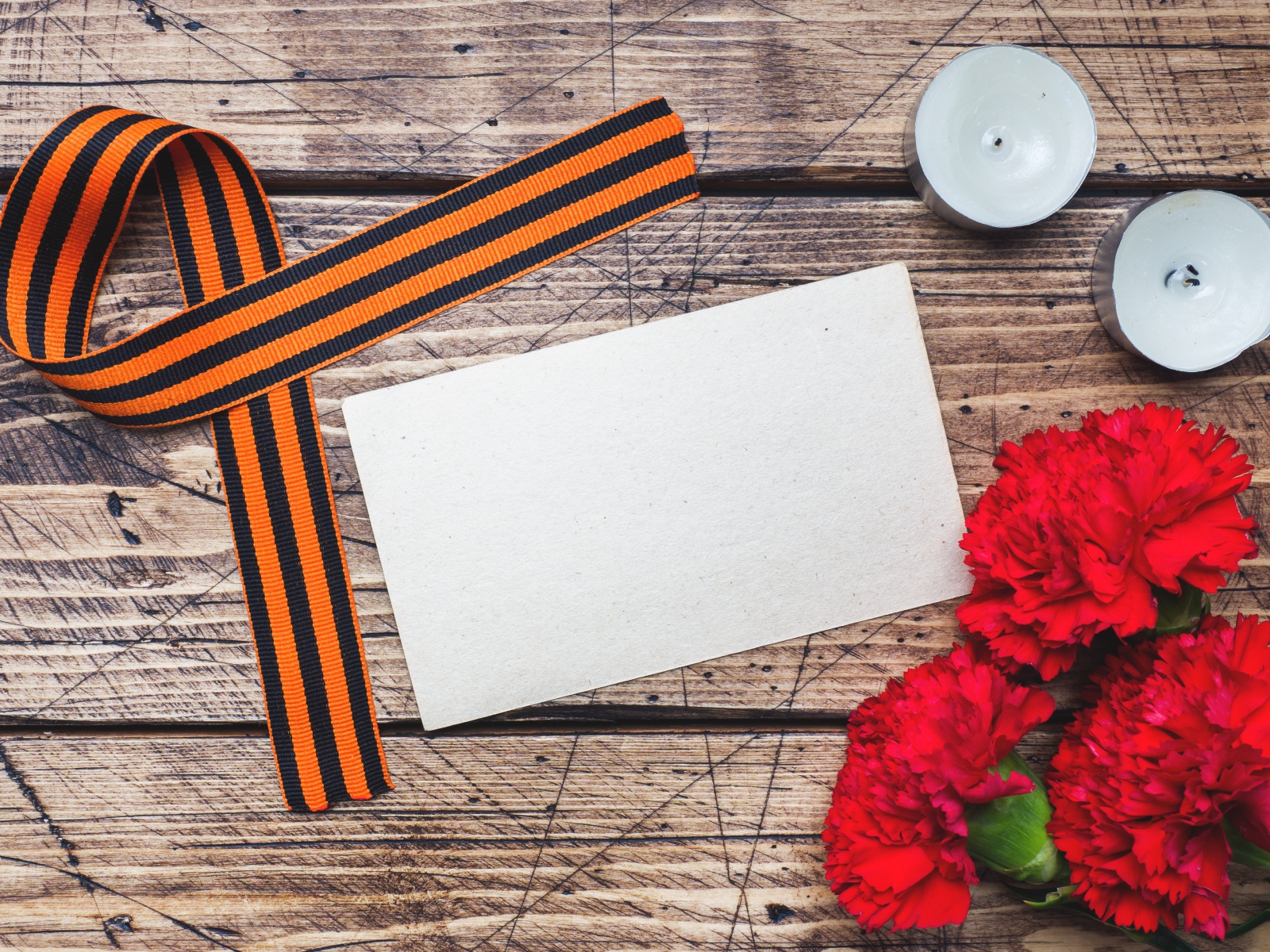 Красные гвоздики, георгиевская лента и свечи на столе, шаблон для открытки на 9 мая День победы