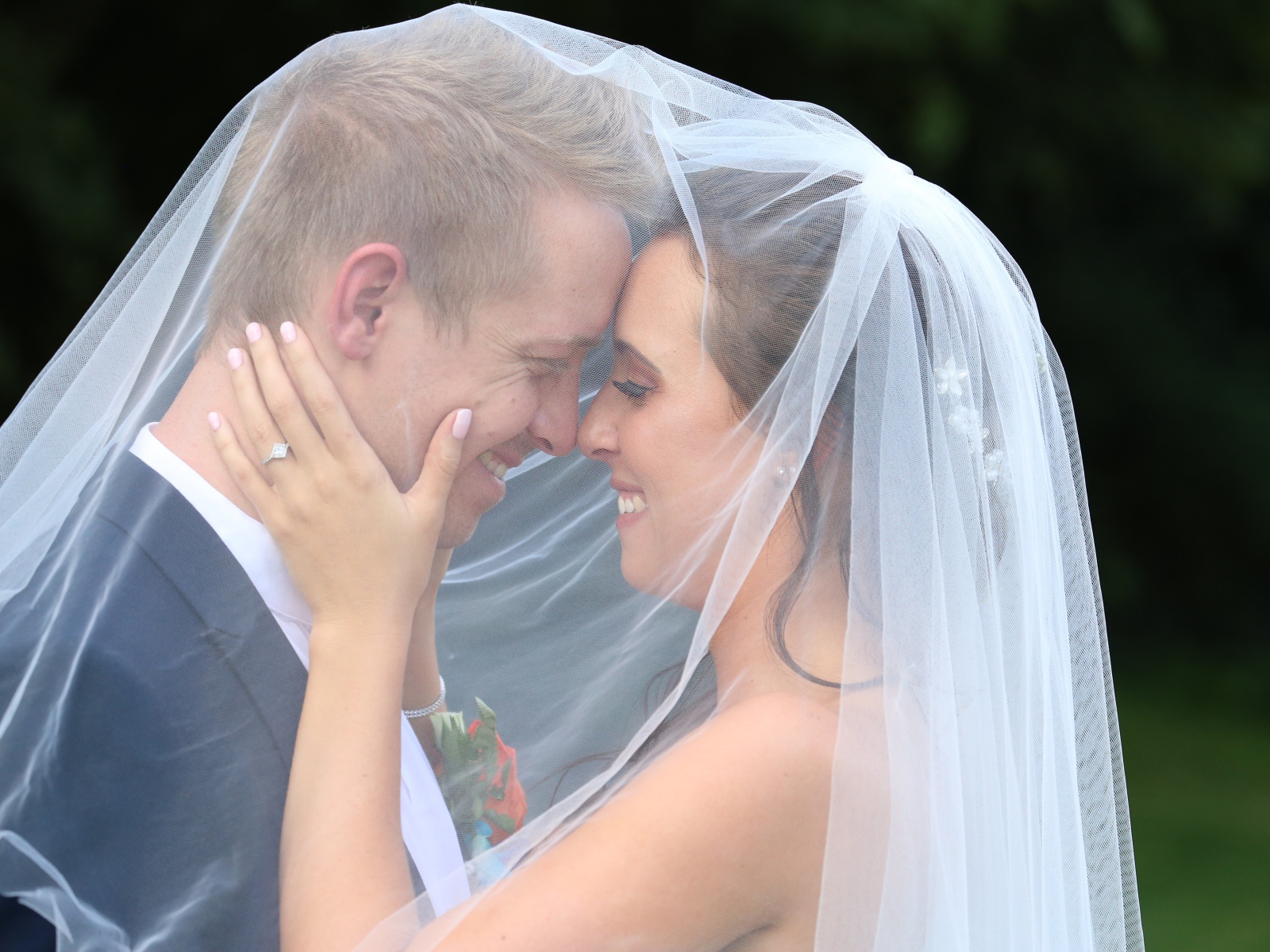 Жених и невеста стоят под белой фатой