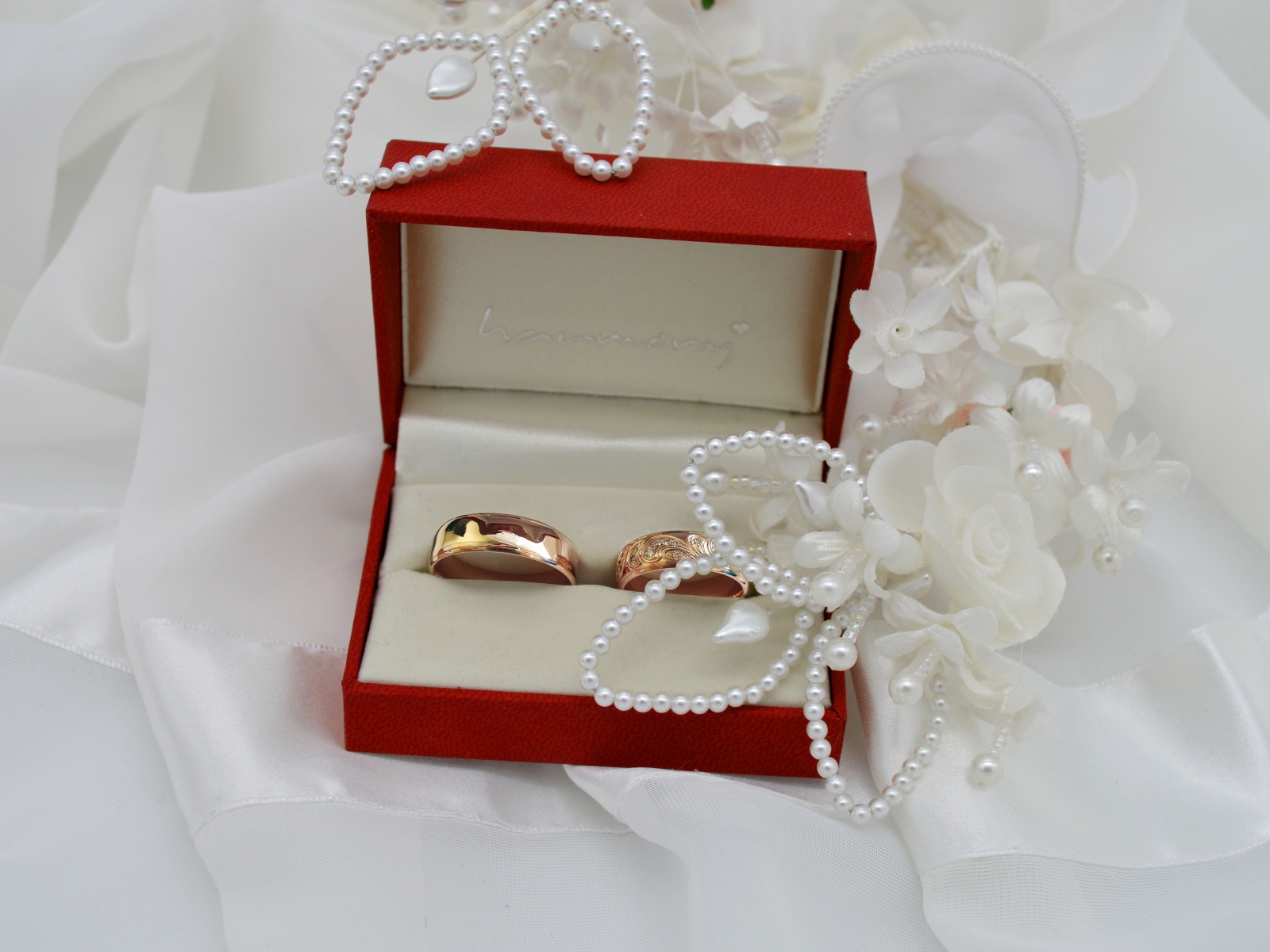 Золотые обручальные кольца в красной коробочке с украшениями