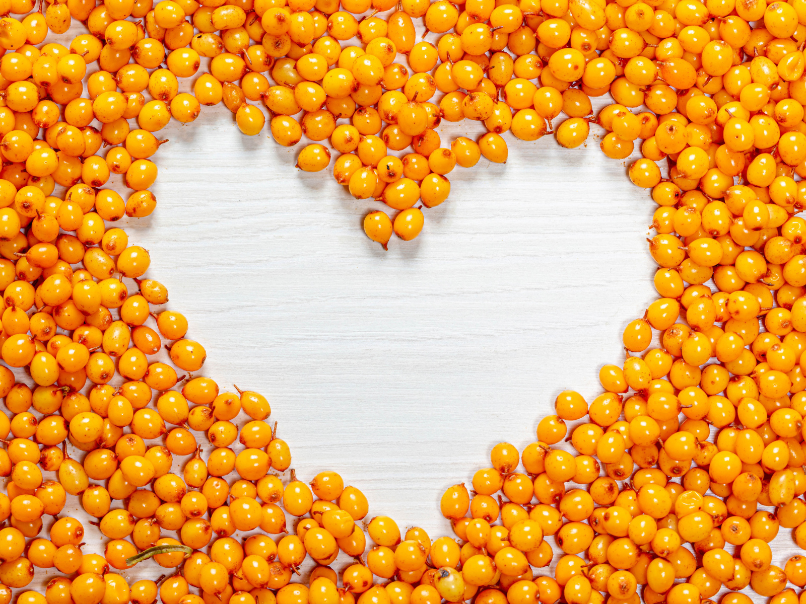 Сердце из ягод облепихи на столе 