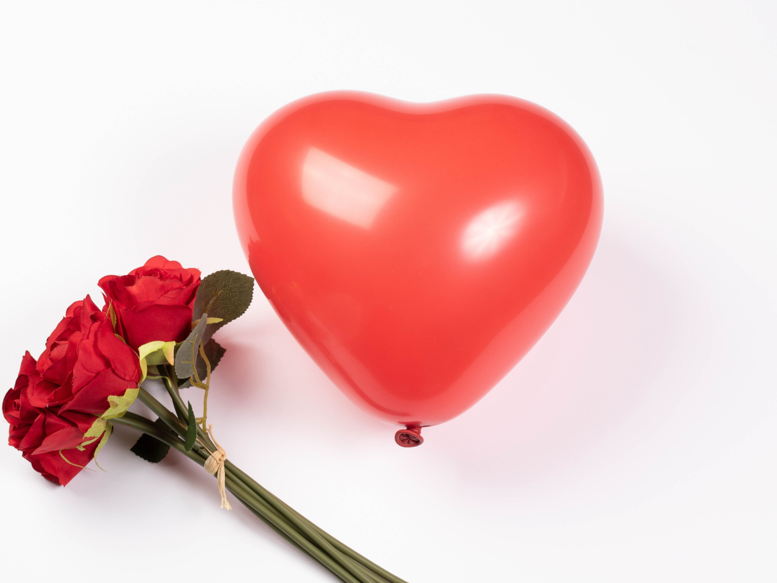 Красный шарик в форме сердца с букетом роз на белом фоне