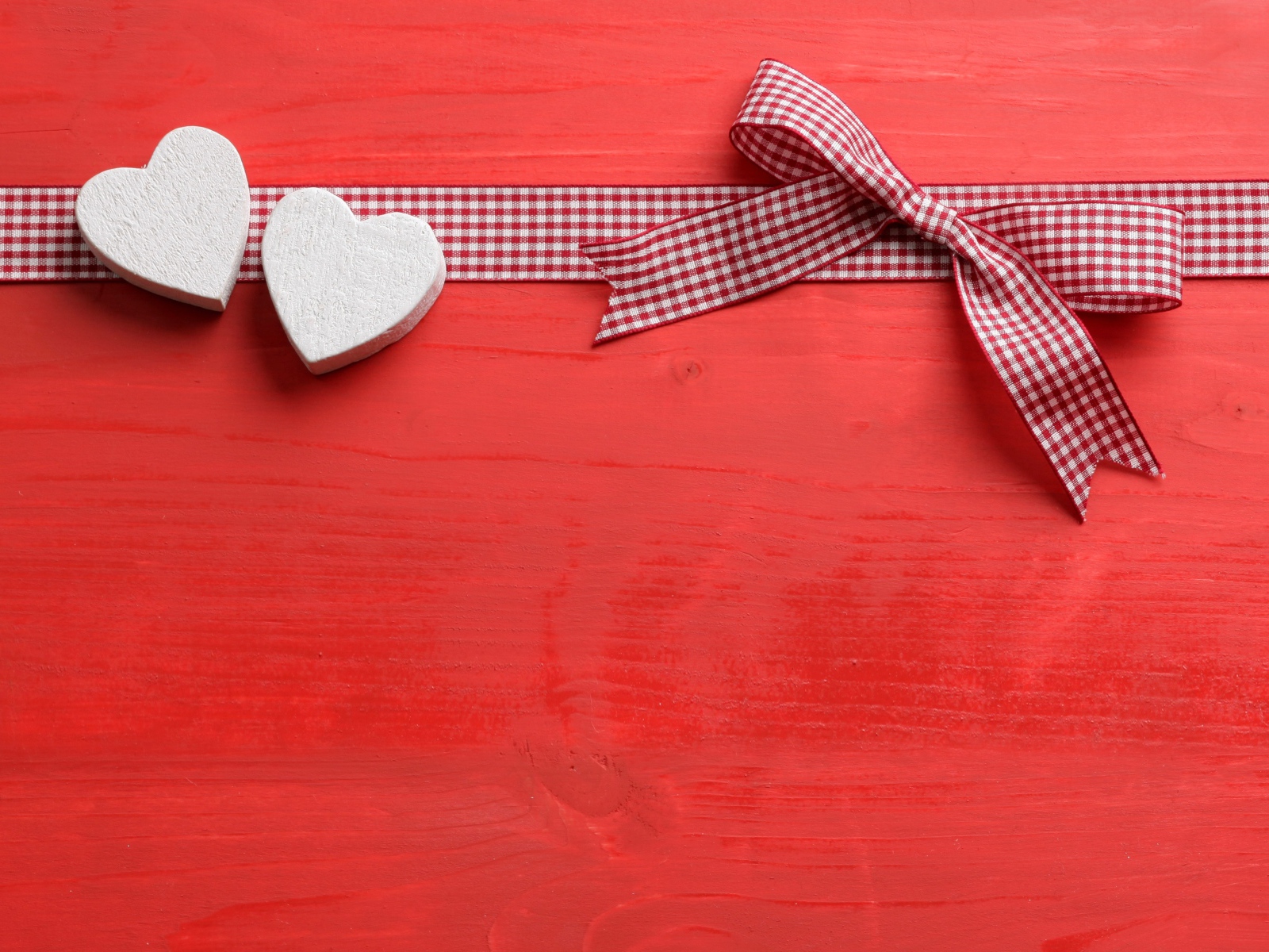 Два сердечка с бантом на красном фоне