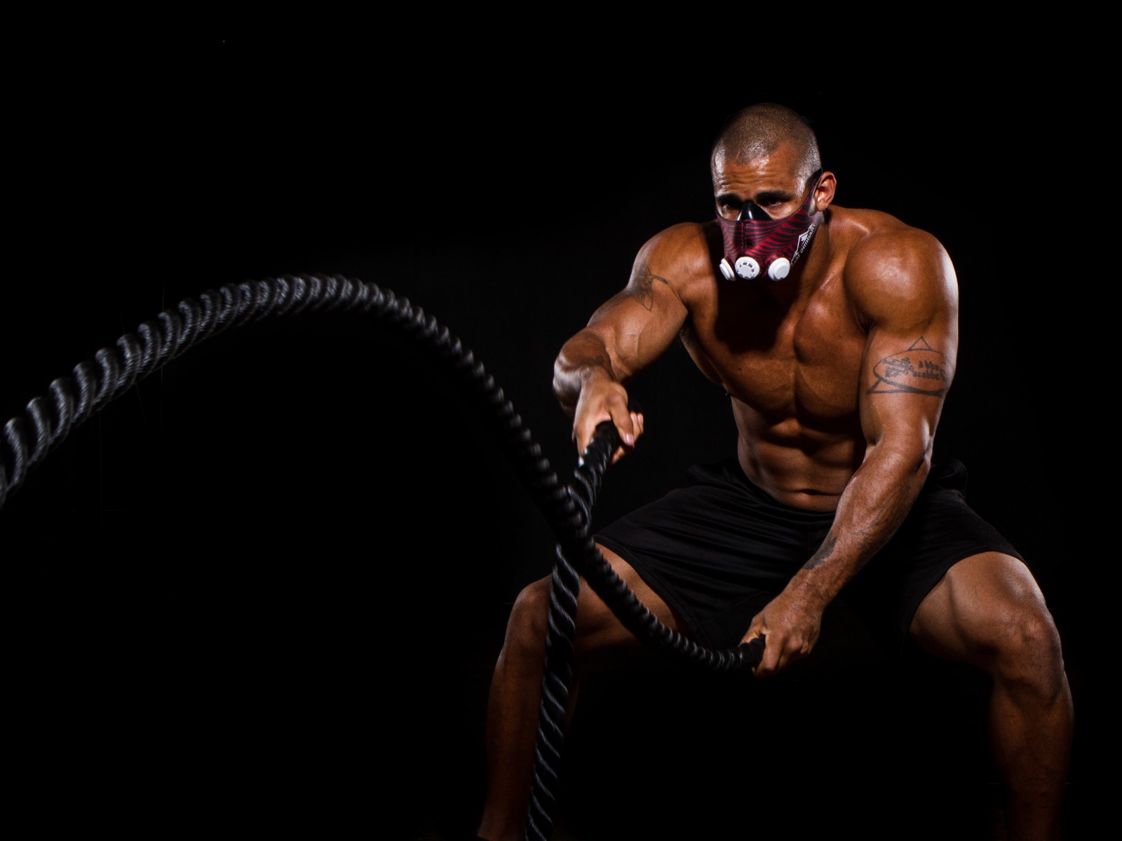 Накаченный мужчина в маске с канатом в руках 