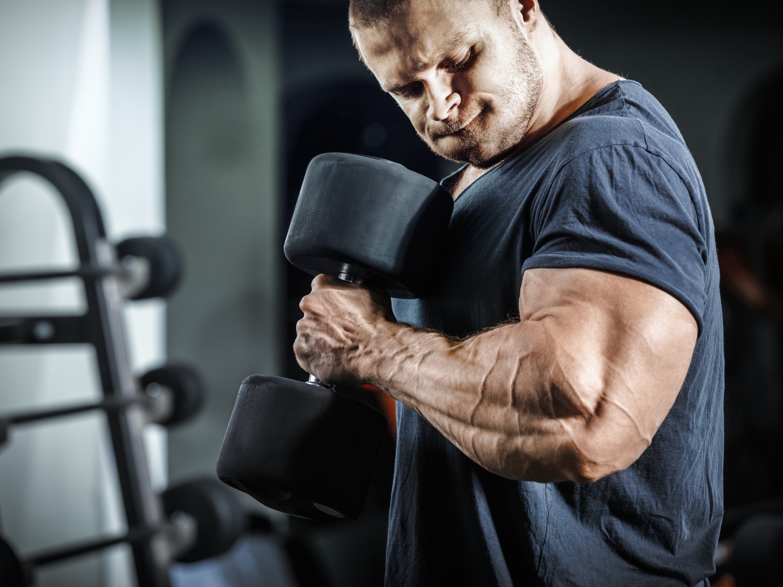 Мужчина бодибилдер в спортзале с гантелей 