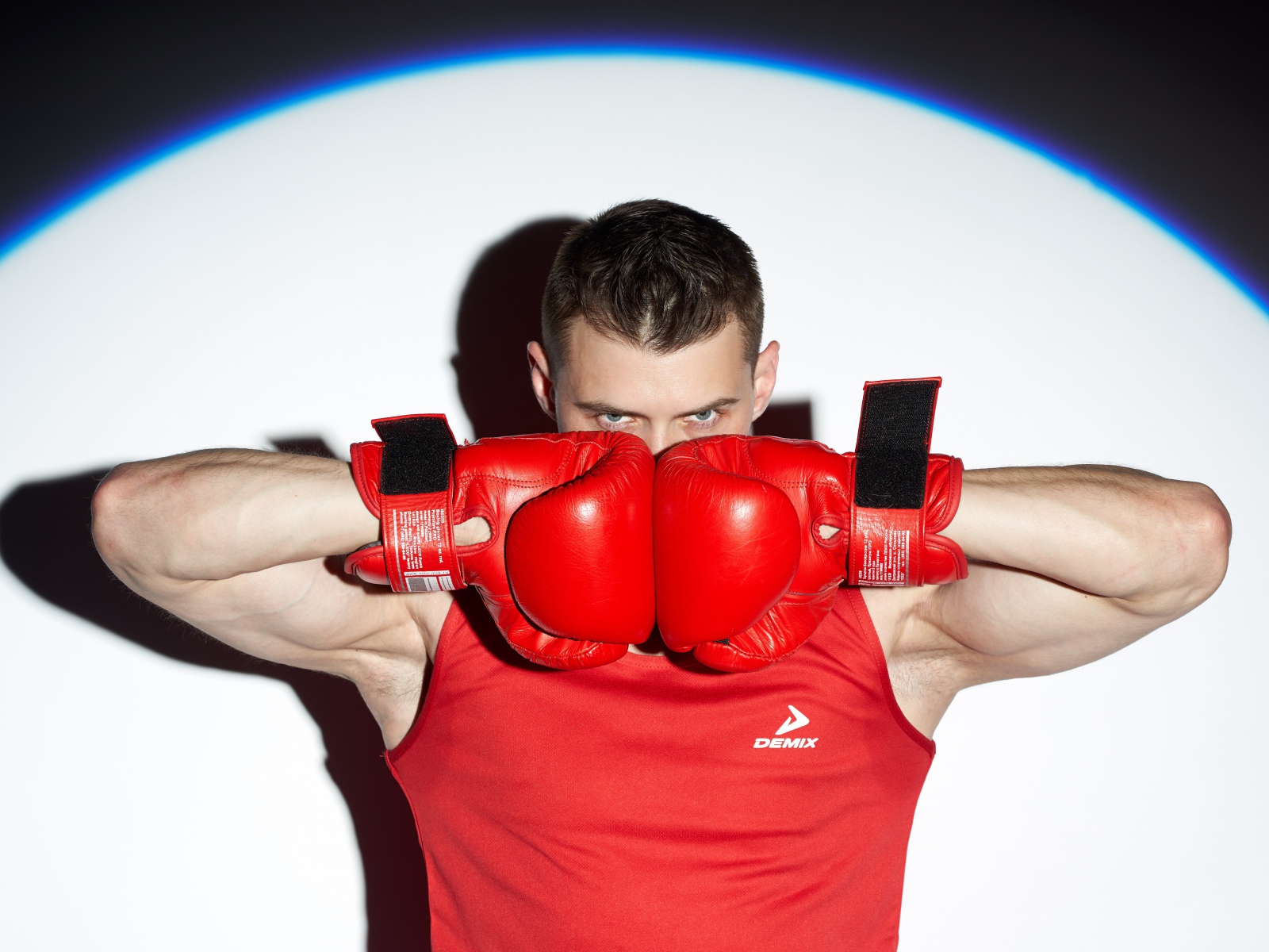 Мужчина боксер с красных перчатках в свете прожектора 