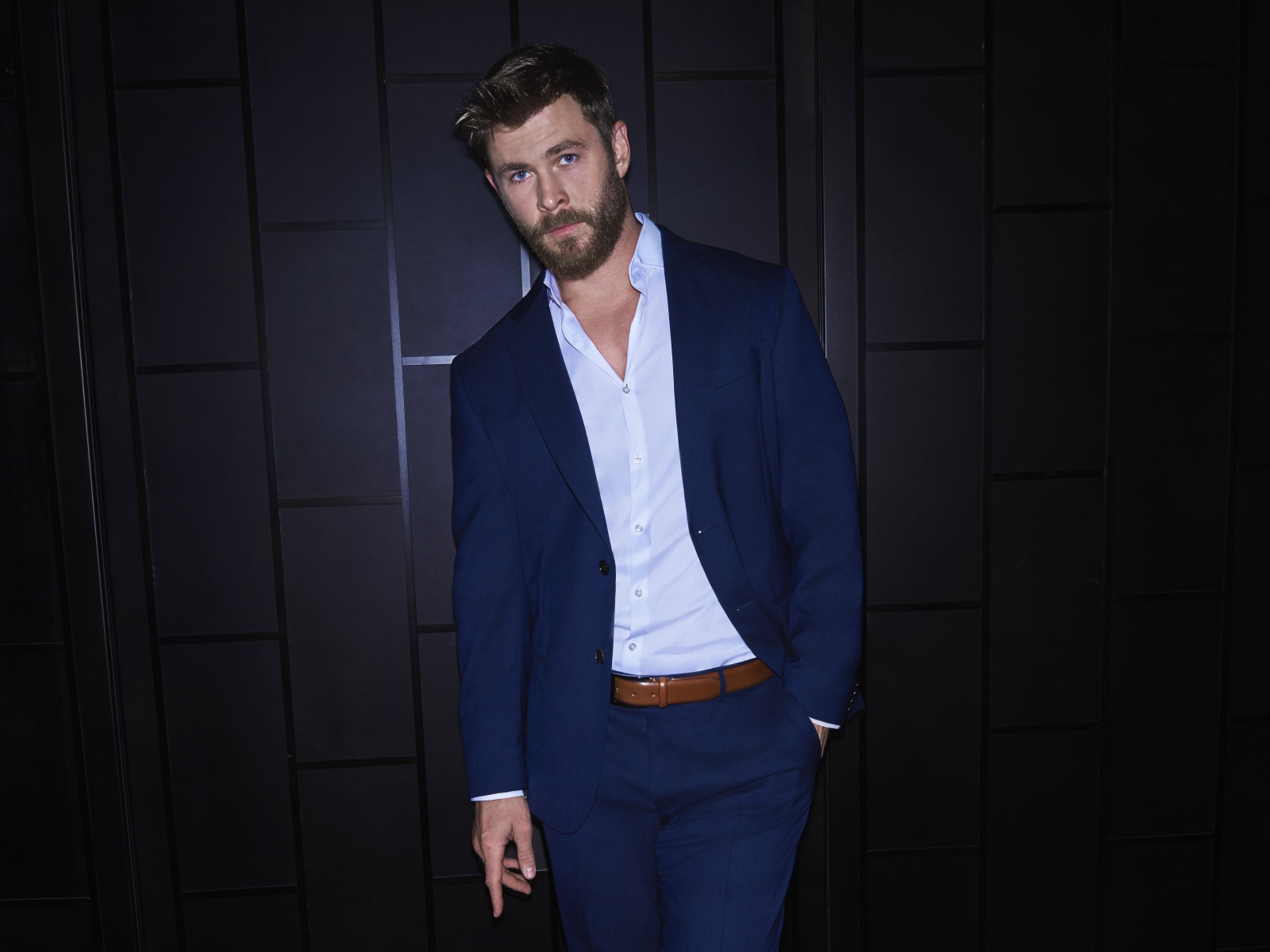 Австралийский актер Крис Хемсворт в костюме у стены