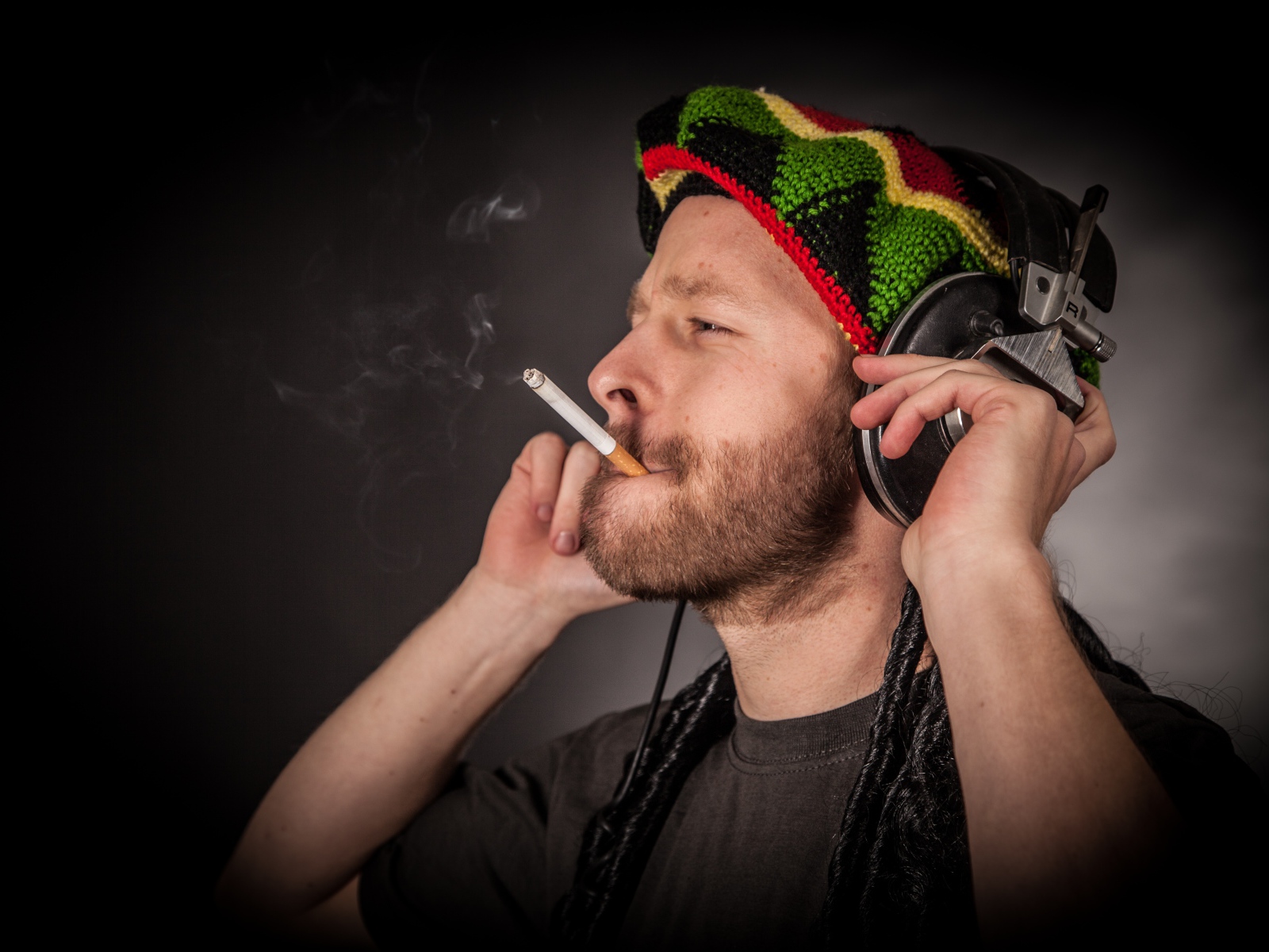 Мужчина растаман в наушниках с сигаретой 