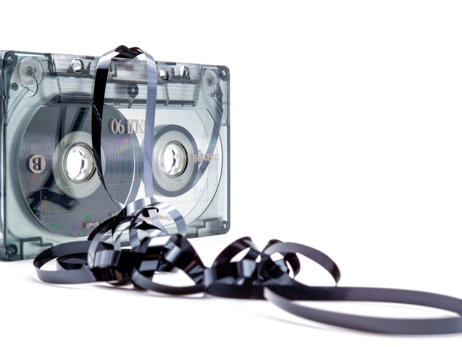 Магнитофонная кассета в размотанной пленкой на белом фоне