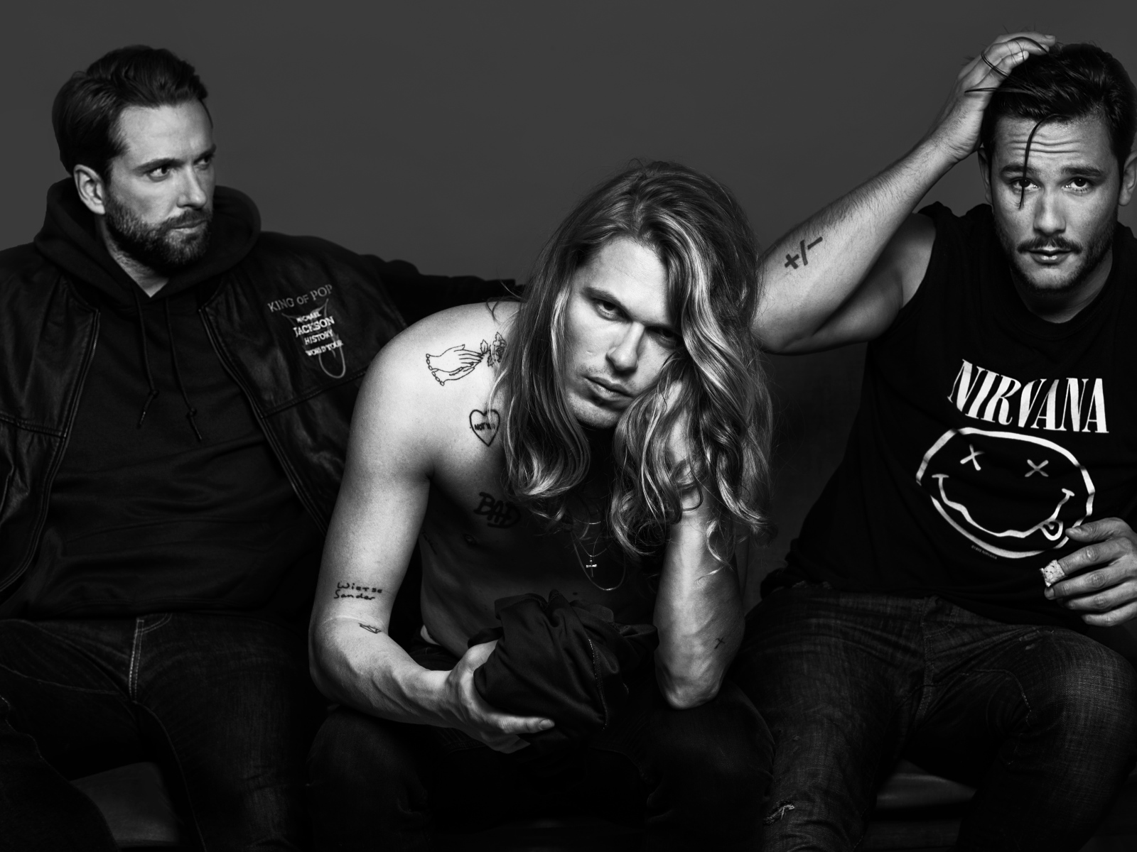 Трио Kris Kross Amsterdam в костюмах на сером фоне