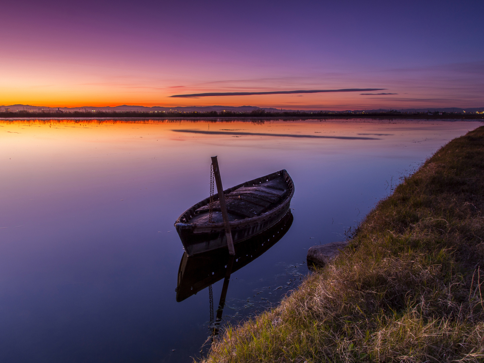 Старая лодка стоит в воде на закате солнца 