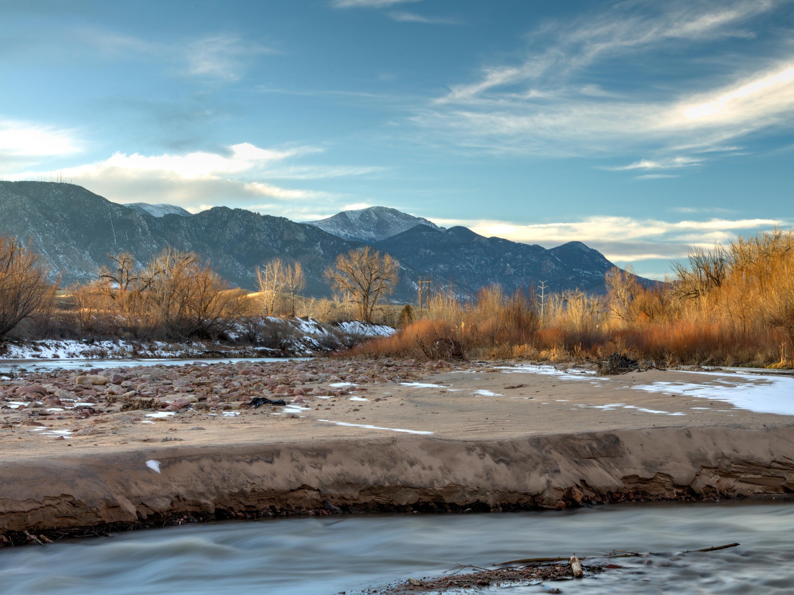 Каменный берег реки на фоне гор под голубым небом 