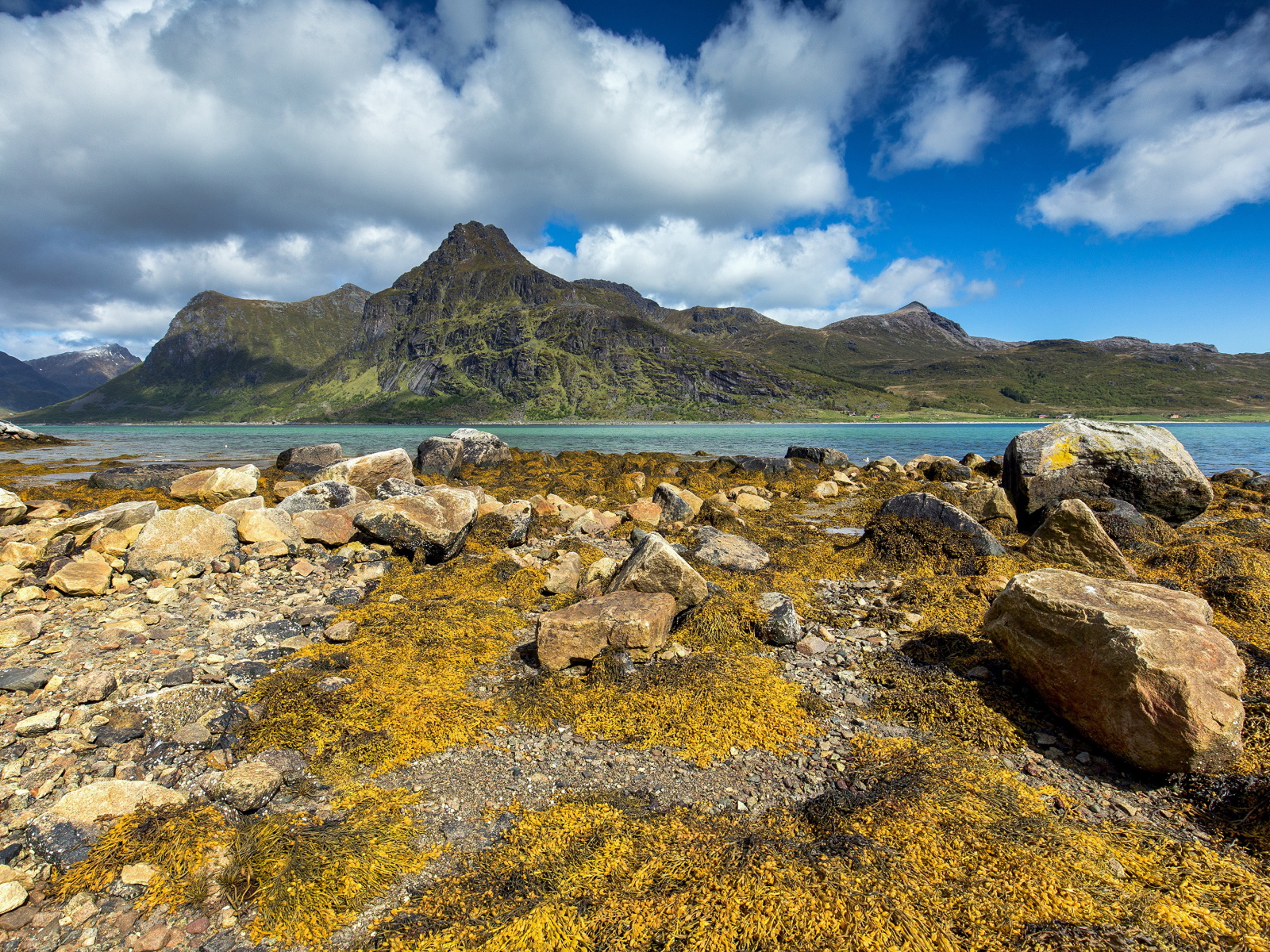 Камни на берегу реки под белыми облаками в голубом небе 