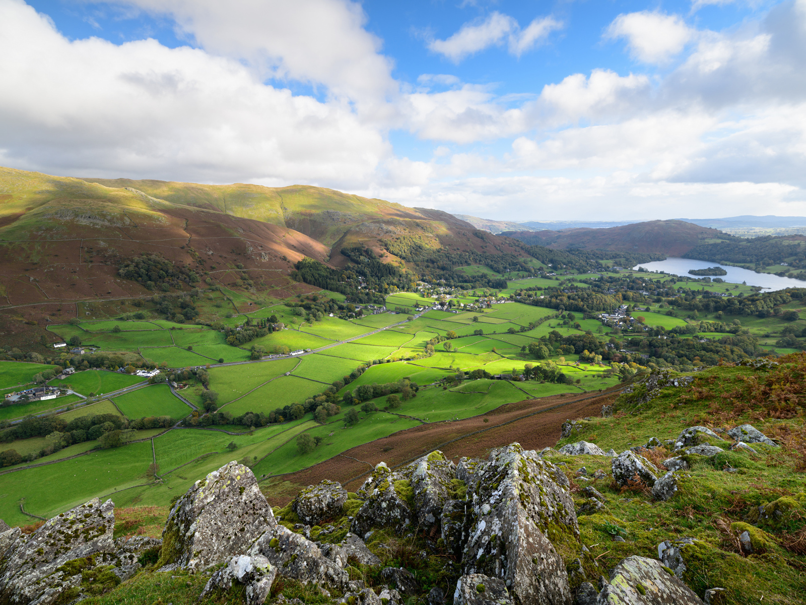 Вид на зеленые холмы под голубым небом с белыми облаками летом