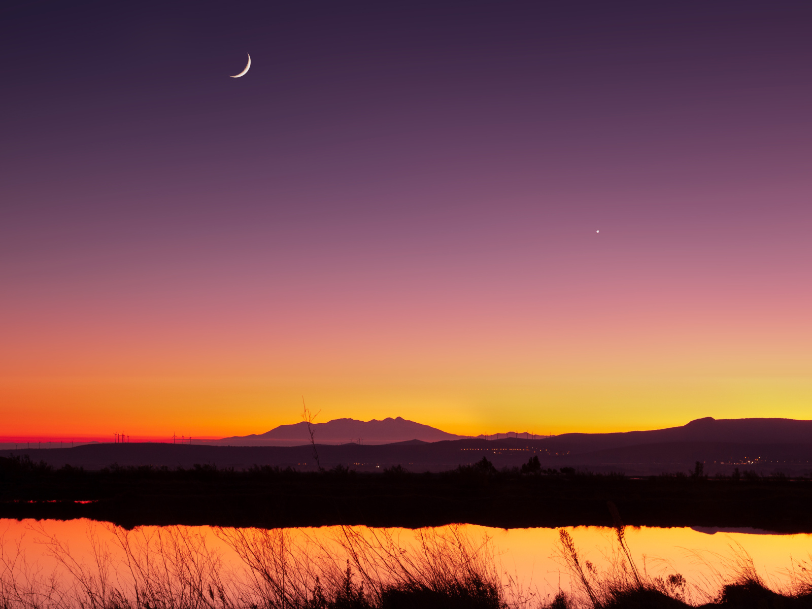 Молодой месяц в небе над озером ночью 