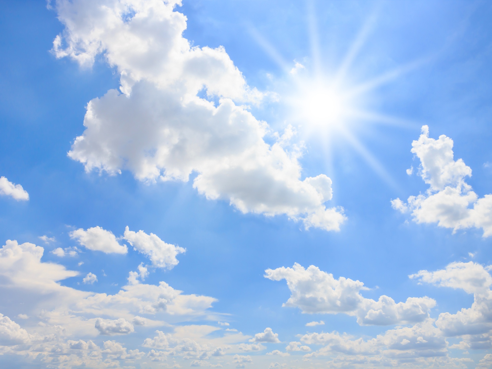 Яркое солнце в голубом небе с белыми облаками