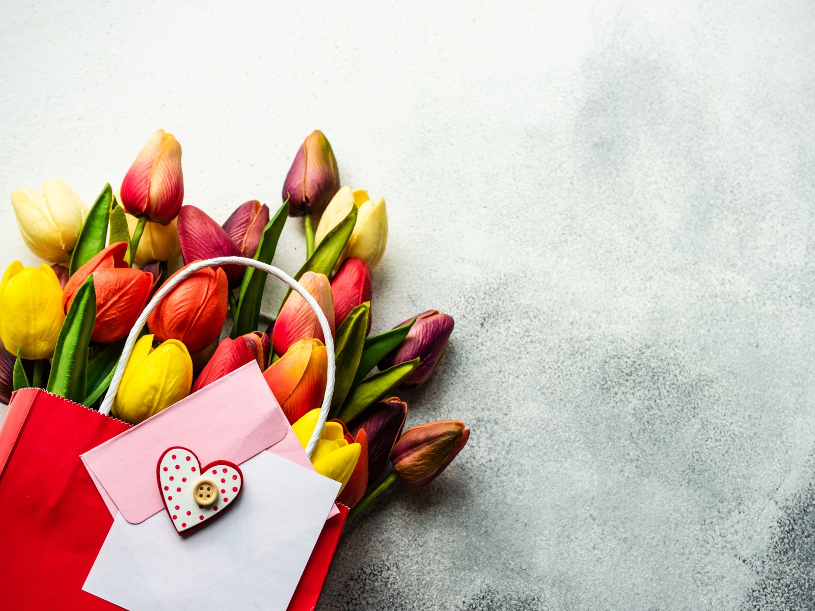 Букет разноцветных тюльпанов с письмом на сером фоне