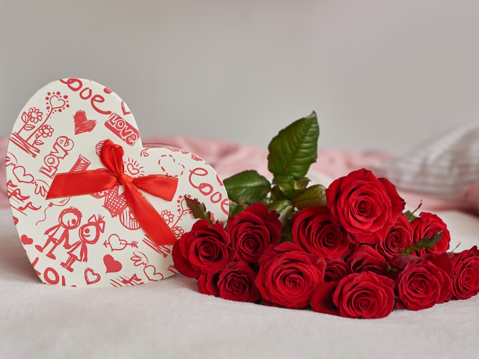 Букет красных роз с коробкой в форме сердца на кровати 